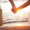 a honeymooning couple holding hands on the beach in front of the sunset