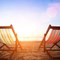 two empty beach chairs in front of an ocean sunset