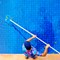 Young man cleans out a dirty pool